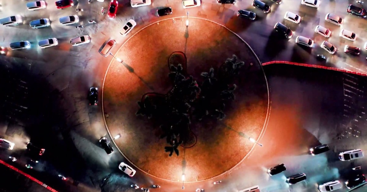 Aerial view of a roundabout with cars and trees.
